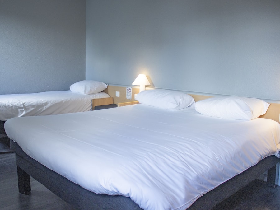 Ein Hotelzimmer mit zwei Einzelbetten, jeweils mit Nachttisch und Lampe.
