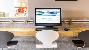 Un espacio de trabajo moderno con una computadora, teclado y dos sillas. Un cartel en la pared enumera varios términos relacionados con internet.