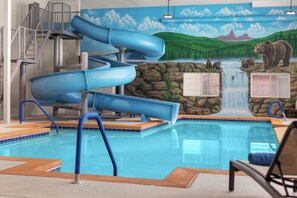 A pool area with a water slide, a waterfall feature, and a mural of a bear and landscape.