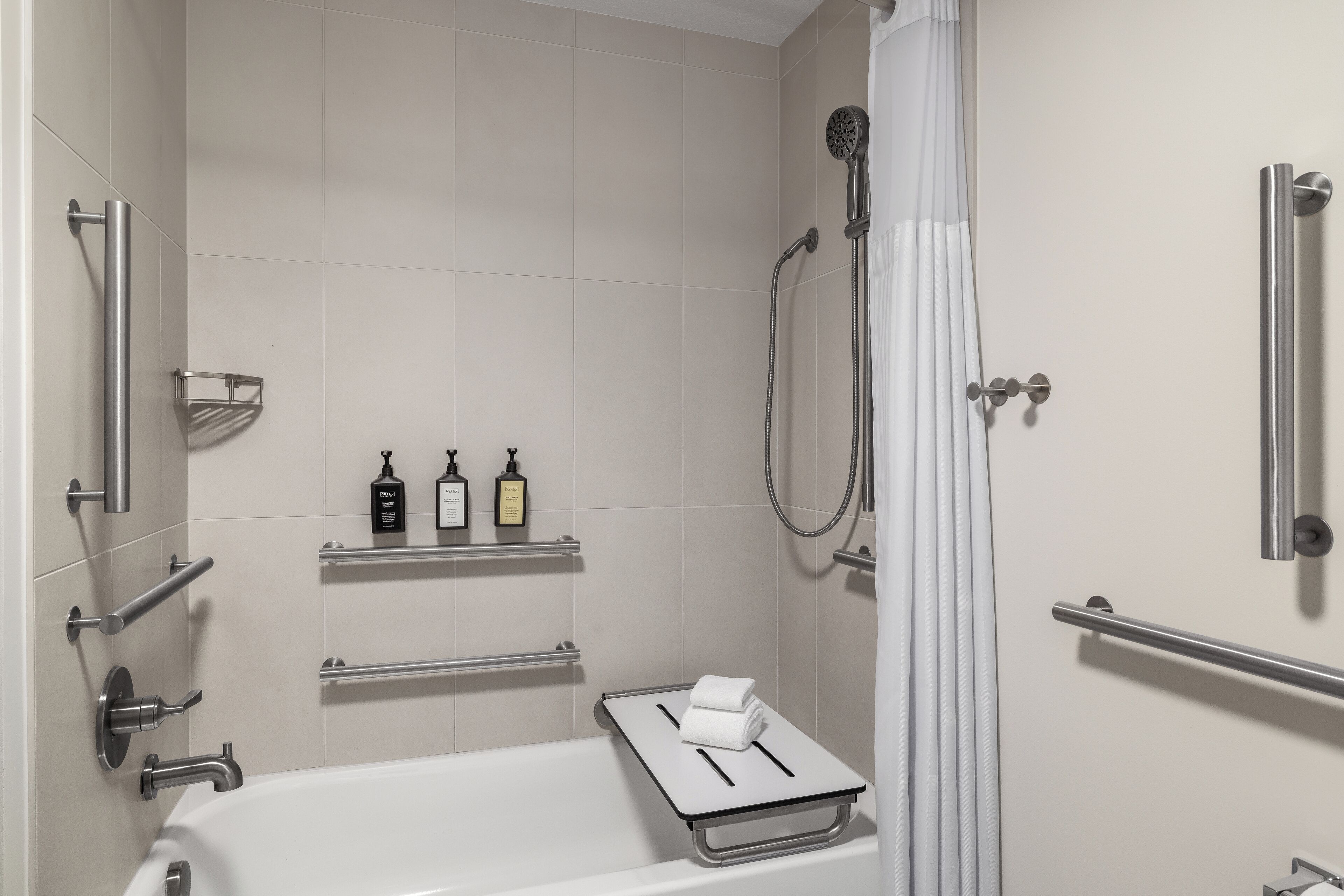 A modern bathroom with a bathtub, a shower, and a towel rack.