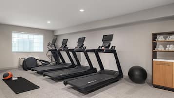 A gym with treadmills, a stationary bike, and a rowing machine.