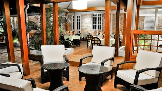 A restaurant with wicker furniture, stone walls, and a wooden floor.