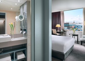 A hotel room with a bathroom featuring a modern sink, mirror, and towel rack. - Hilton Prague Old Town (Prague)