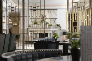 Una sala de estar moderna con un sofá de cuero negro, una mesita de centro y un separador decorativo con plantas.