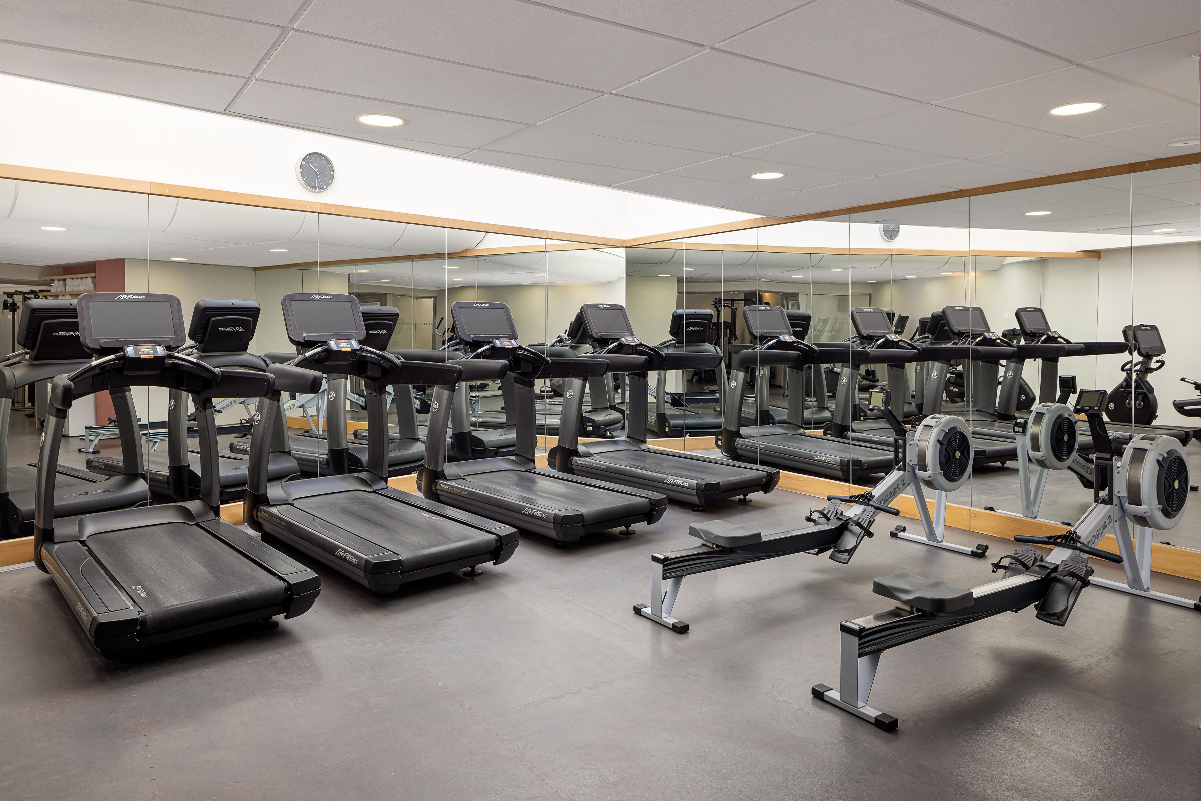 A gym with multiple treadmills, exercise bikes, and a mirrored wall.