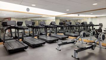 A gym with multiple treadmills, exercise bikes, and a mirrored wall.