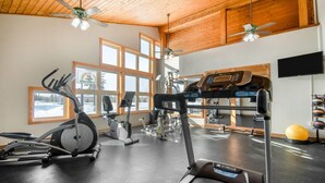 A gym with various exercise equipment, large windows, and a wooden ceiling. - Days Inn by Wyndham International Falls (International Falls)