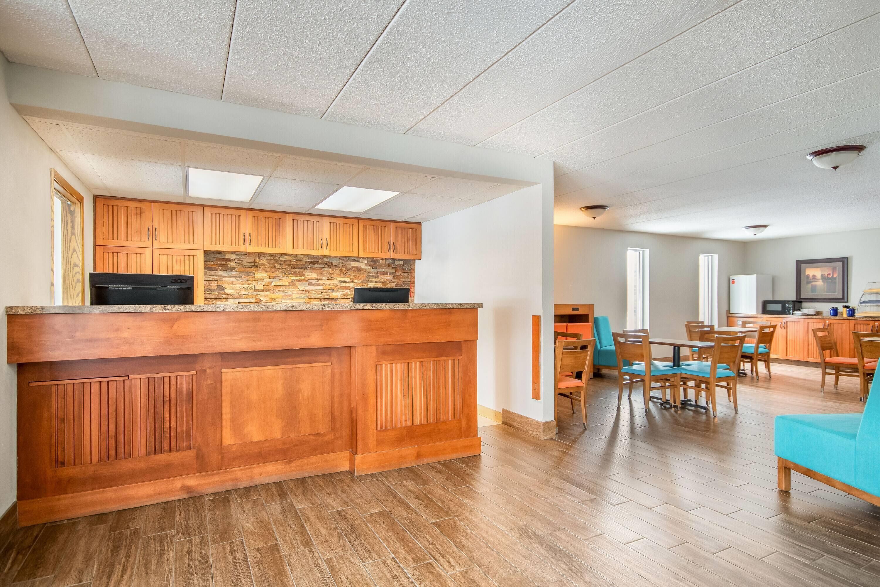 A spacious kitchen with wooden cabinets and a stone backsplash, leading to a dining area with a teal sofa and wooden chairs.