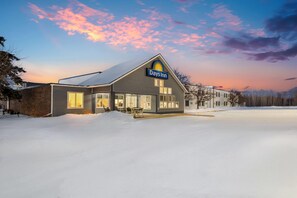 A Days Inn hotel with a large, well-lit entrance and a snow-covered parking lot. - Days Inn by Wyndham International Falls (International Falls)