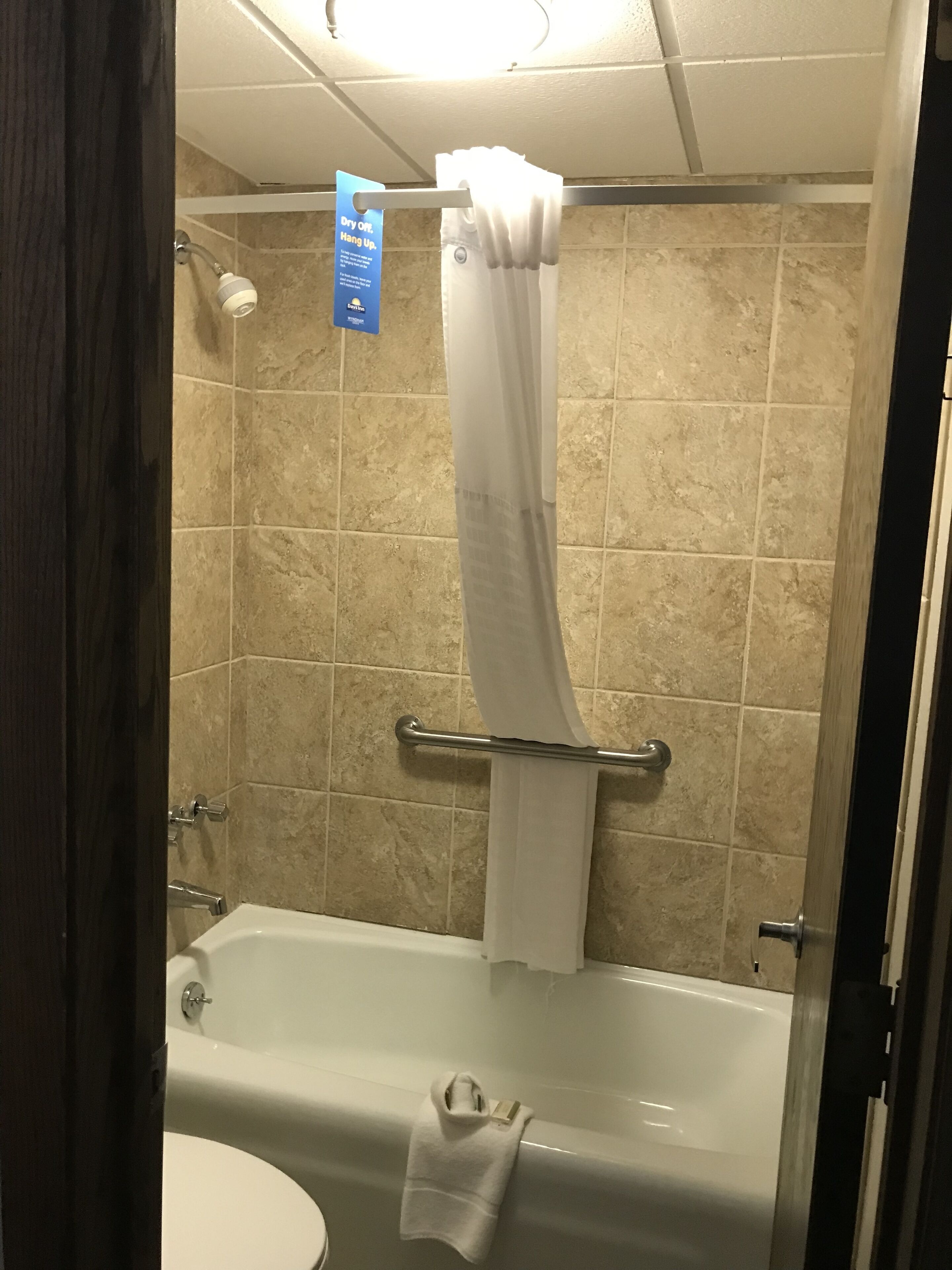 A bathroom with a bathtub, a shower curtain, and a towel hanging on the wall.