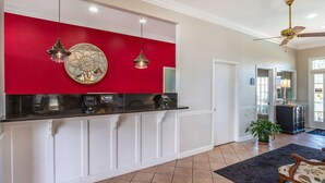 A modern kitchen with a red accent wall, white cabinetry, and a built-in espresso machine.