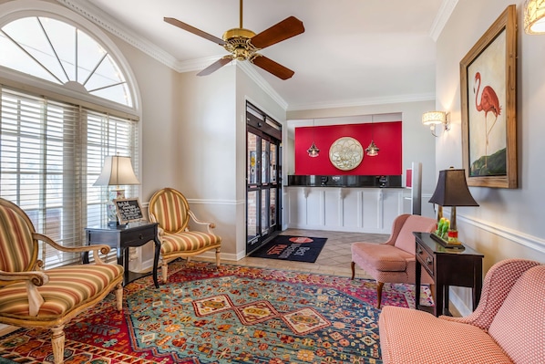A spacious living room with a large window, a ceiling fan, and a vibrant red accent wall.