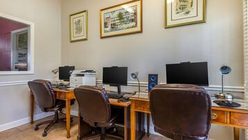 A home office with a desk, two chairs, a computer, and two monitors. There are framed pictures on the wall.