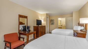 A hotel room with two beds, a desk with a television, a chair, and a dresser.