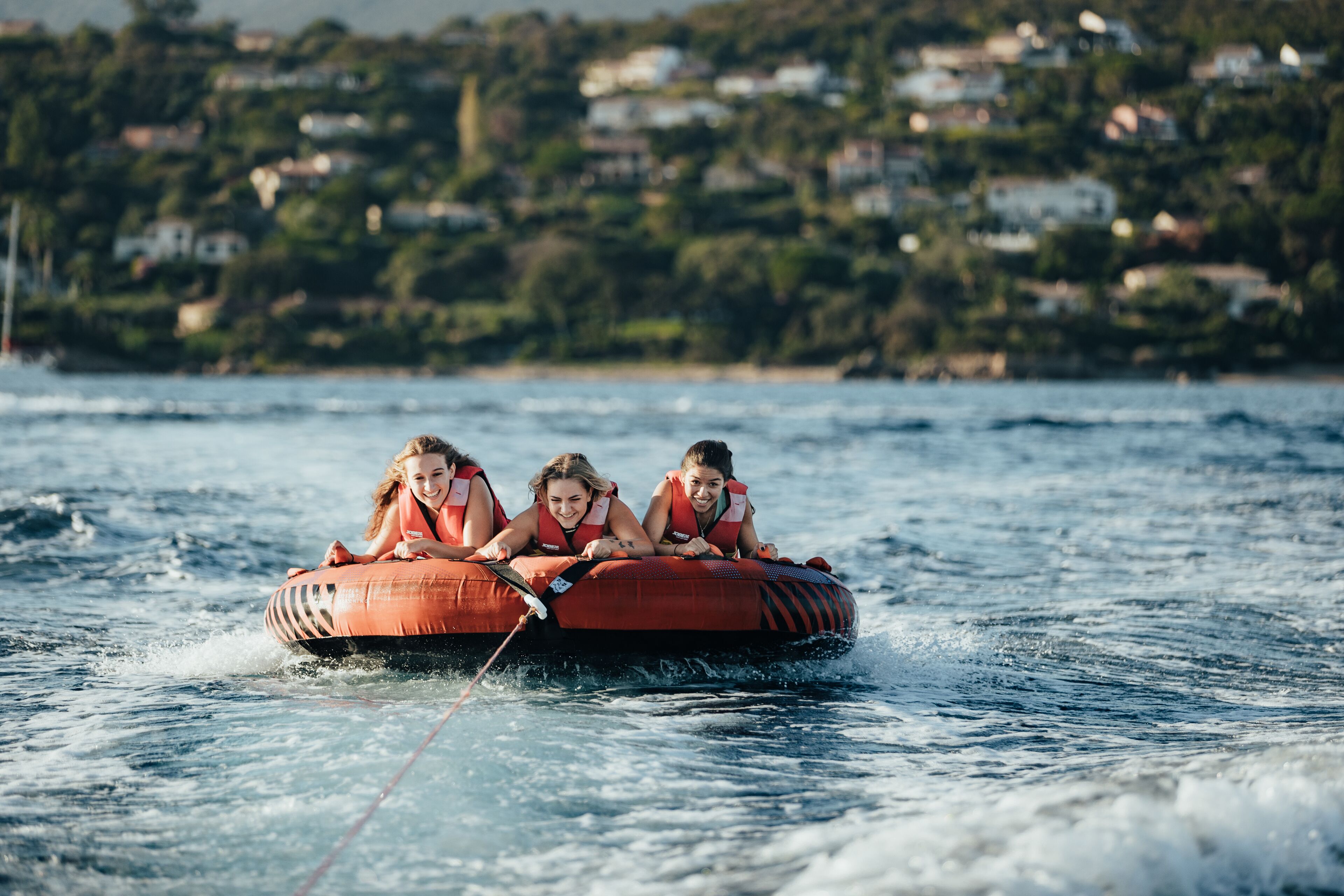Three people on a watercraft with a residential area in the background.