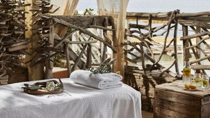 A rustic outdoor seating area with a wooden table, a towel, and a bottle of water. - Sofitel Golfe Ajaccio Thalassa Sea & Spa (Grosseto-Prugna)
