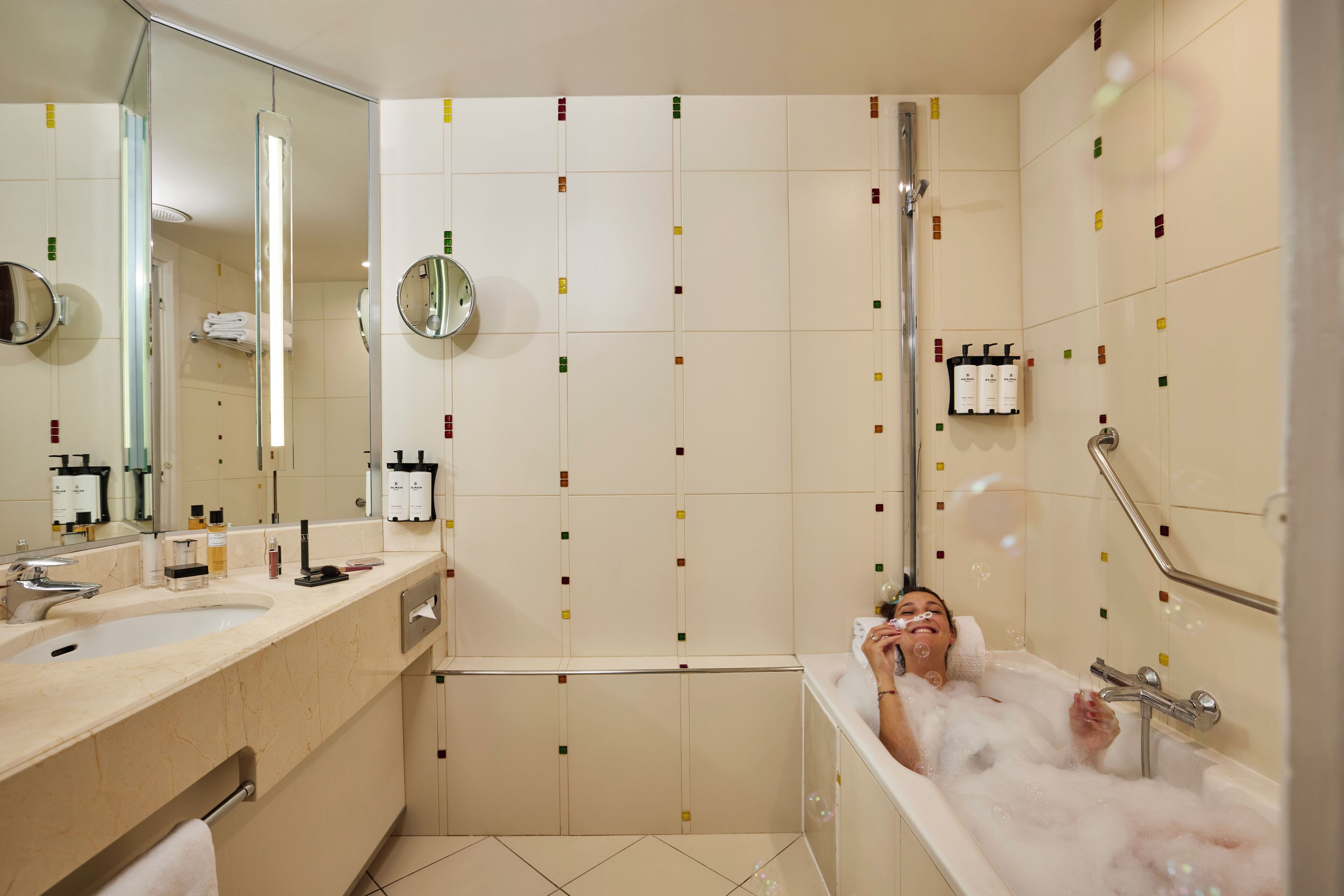 A bathroom with a bathtub, a sink, and a mirror. There are toiletries on the wall and a towel rack.
