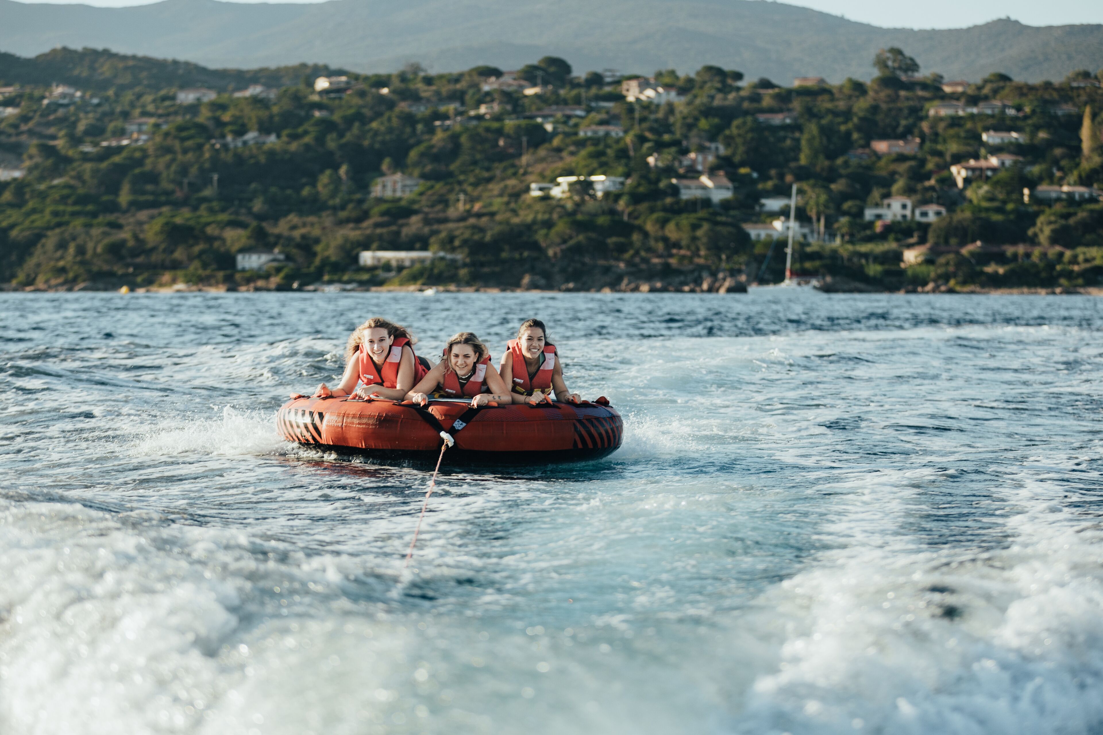 A group of people on a watercraft with a mountainous landscape in the background.