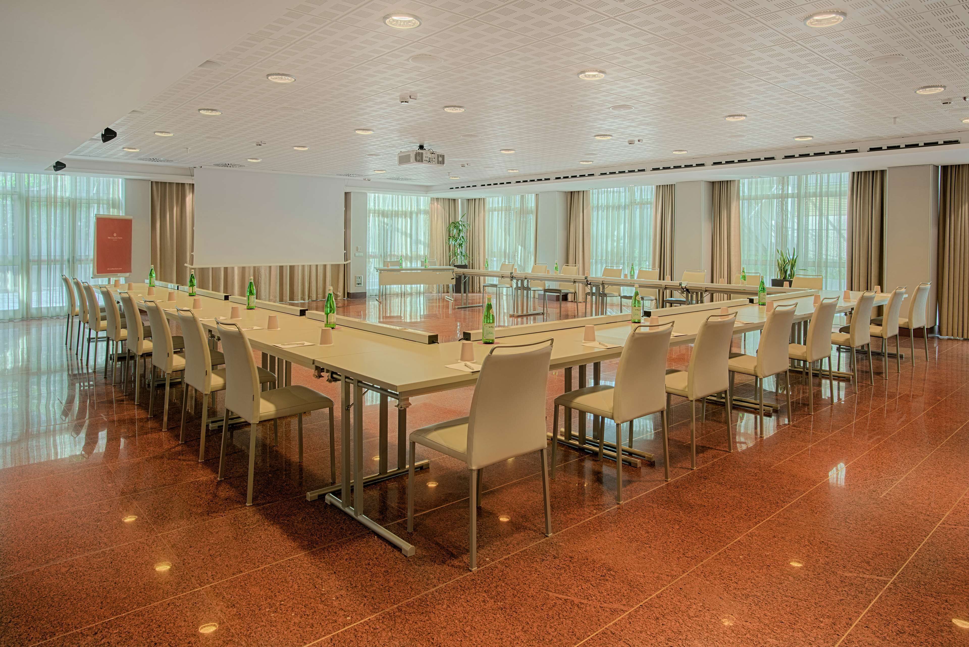 Une salle de conférence équipée d’une longue table, de chaises et d’un écran de projection.