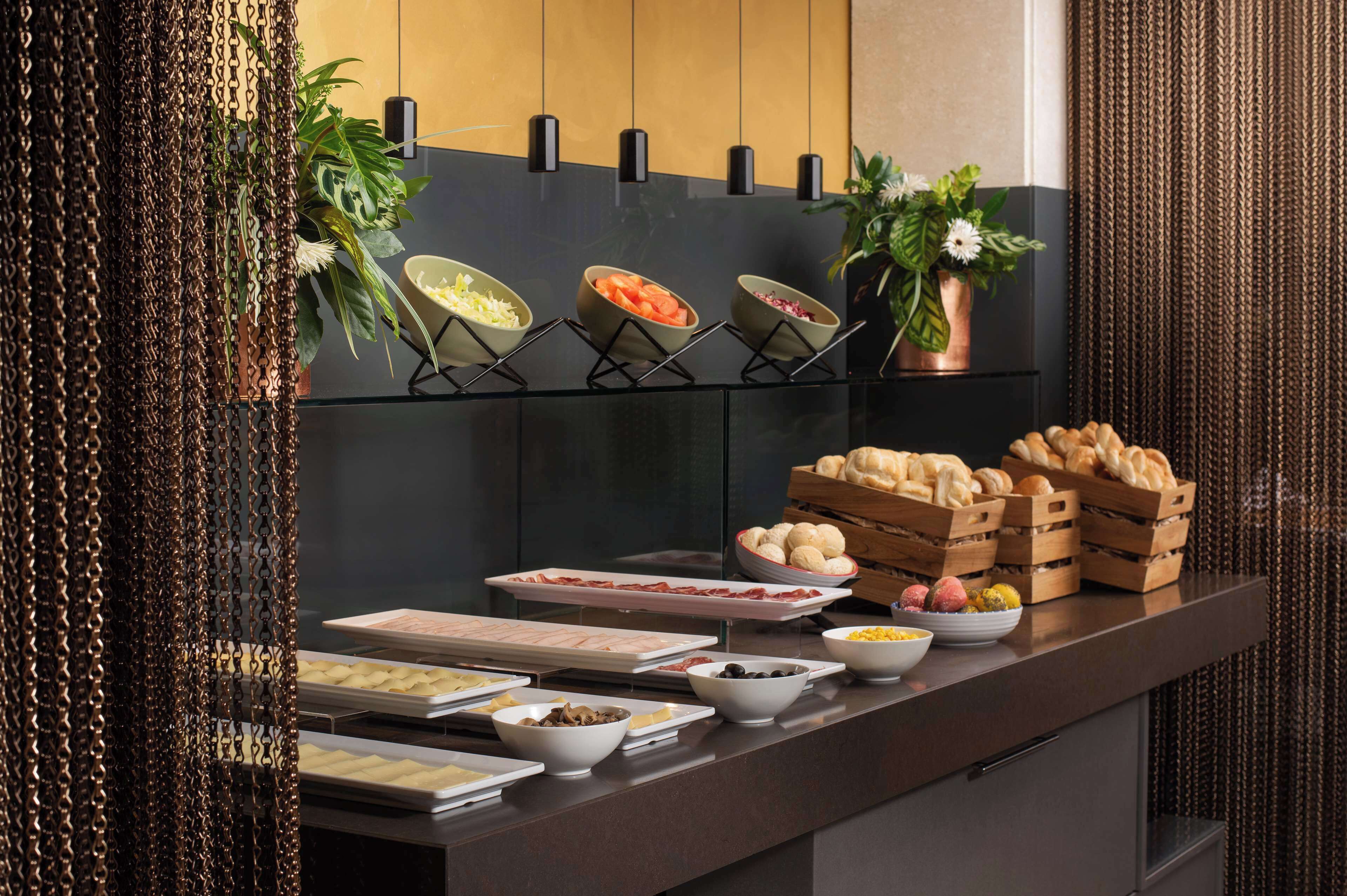 A buffet with various food items, including fruits, vegetables, and breads, arranged on a counter with a modern design.