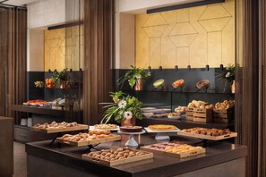 A buffet with various food items and decorative plants.