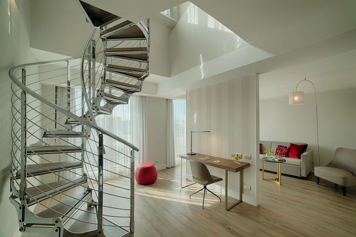A modern interior with a spiral staircase, a dining area, and a sofa set.