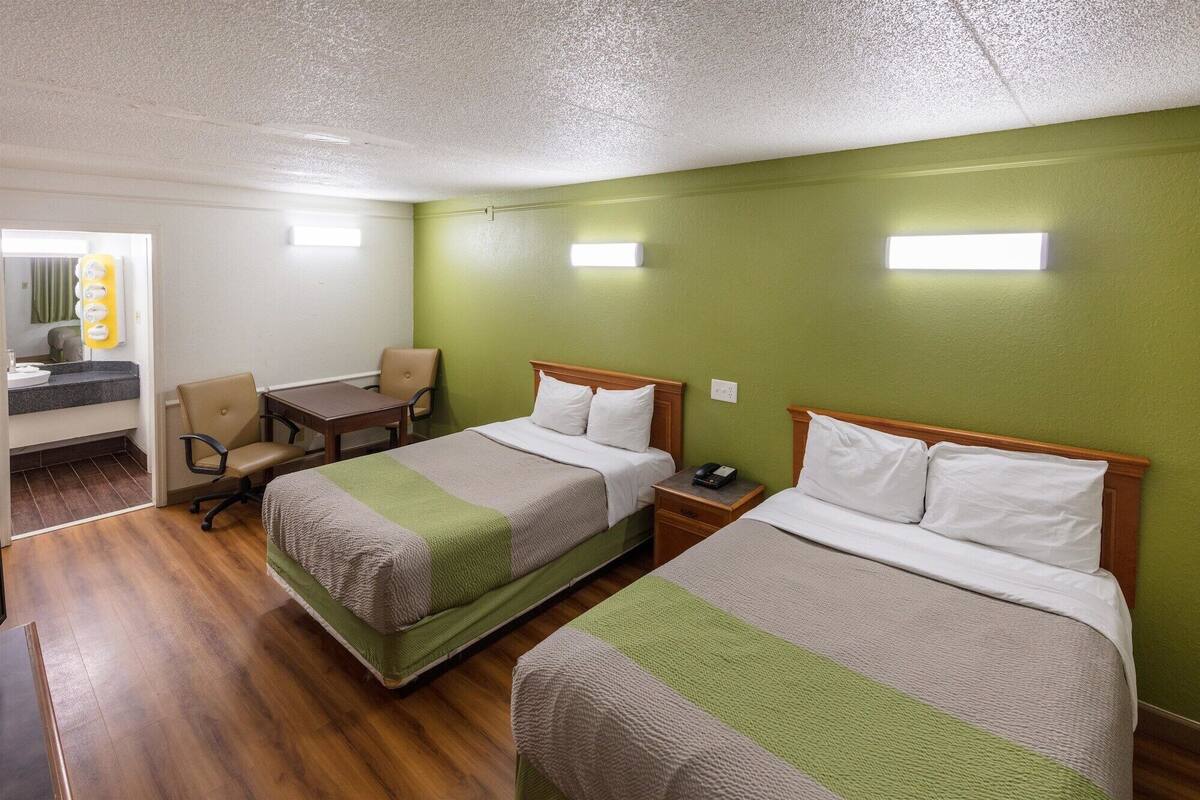 A hotel room with two beds, a desk, and a chair.