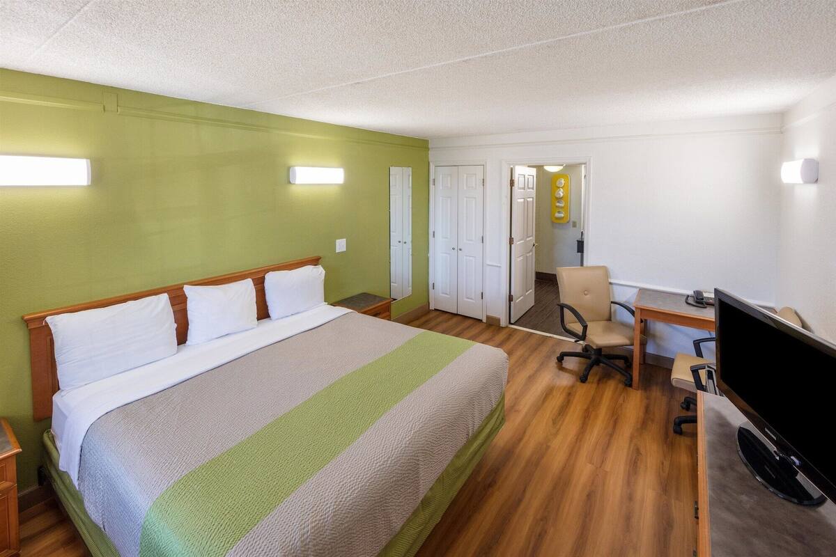 A hotel room with a large bed, a desk with a computer, and a chair.