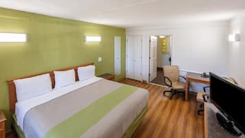 A hotel room with a large bed, a desk with a computer, and a chair.