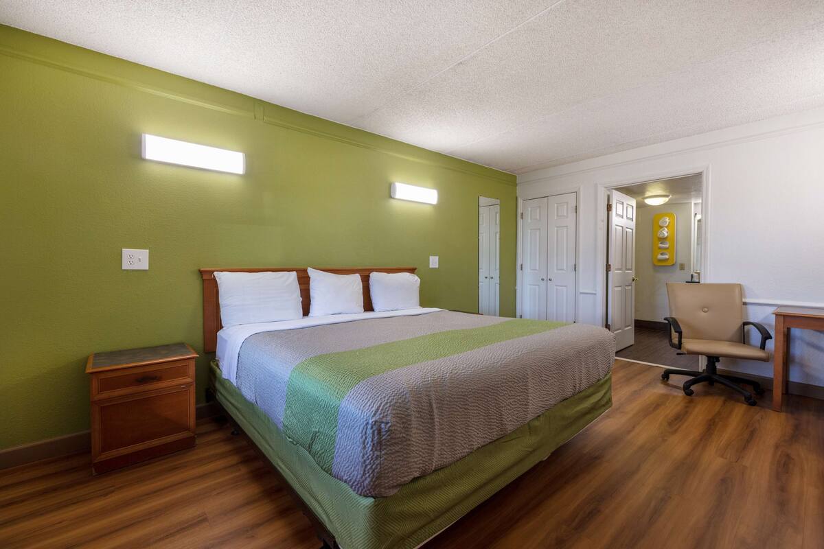 A room with a bed, a nightstand, a desk, and a chair.