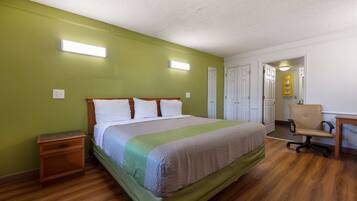A room with a bed, a nightstand, a desk, and a chair.