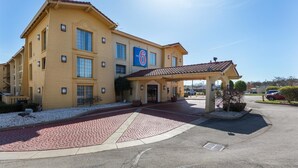 Egy motel, melynek csempével burkolt bejárata és fedett parkolója van.