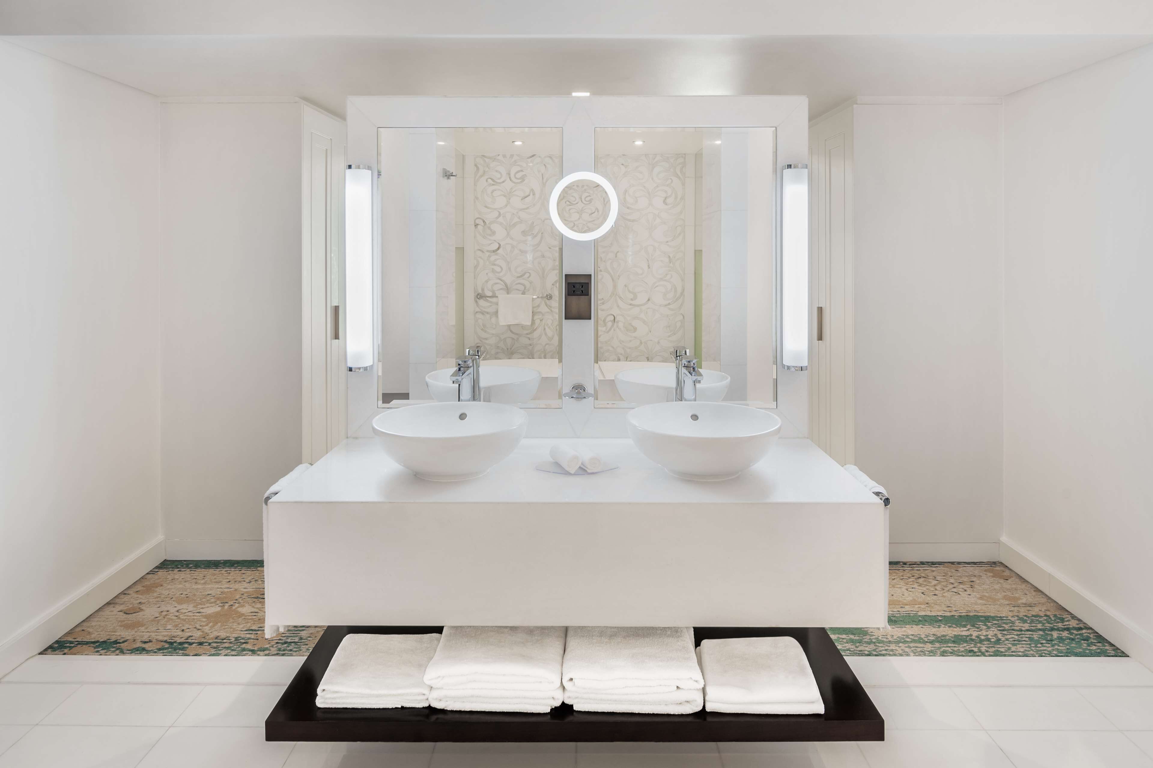 A modern bathroom with two sinks, a large mirror, and a towel rack.