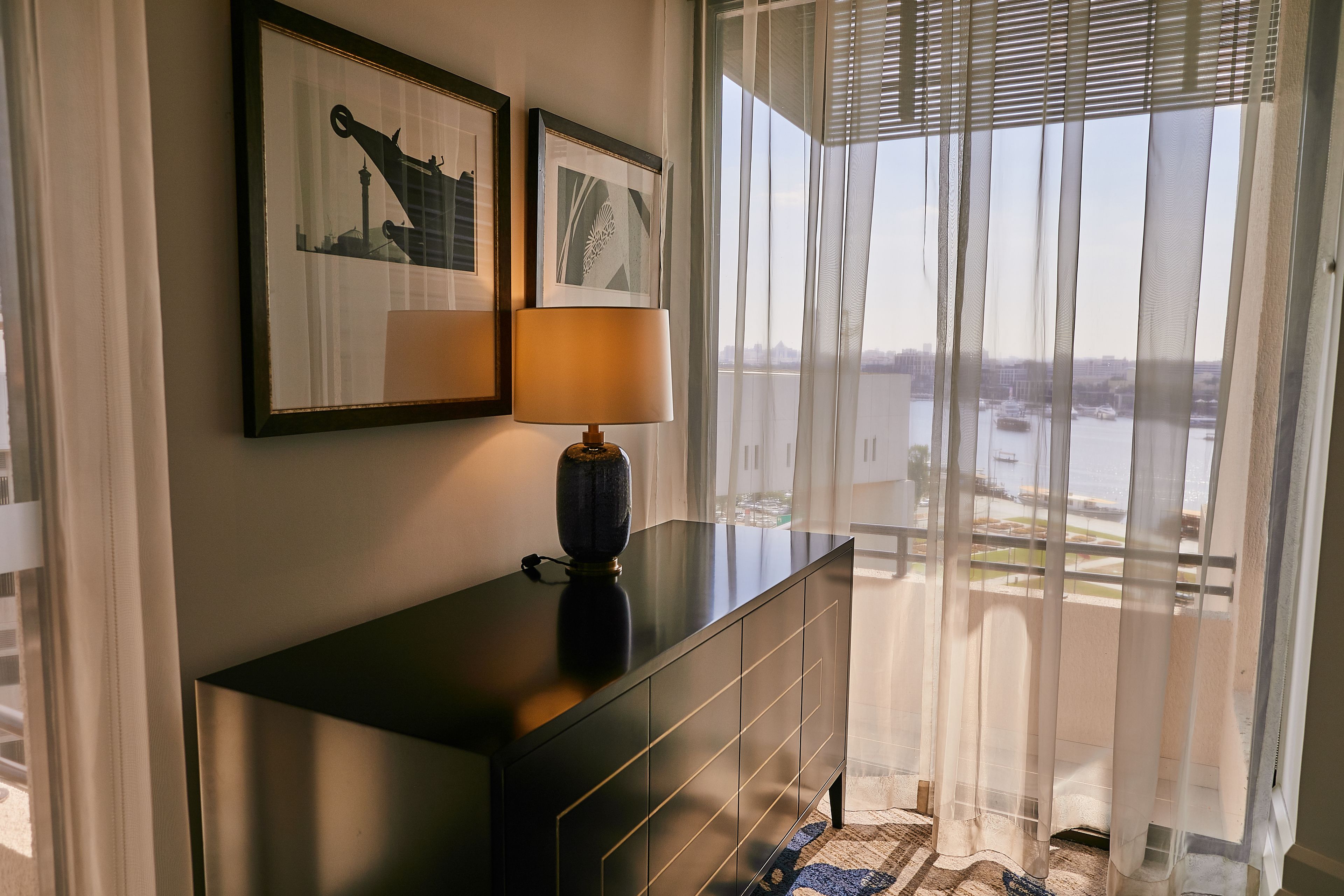 A room with a dark wooden console table, a lamp, and two framed pictures on the wall.