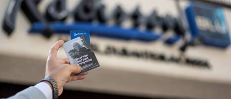 A hand holding a book titled "Rapid Now and Start Learning Today" in front of a blurred background with the word "Reinhold" visible.