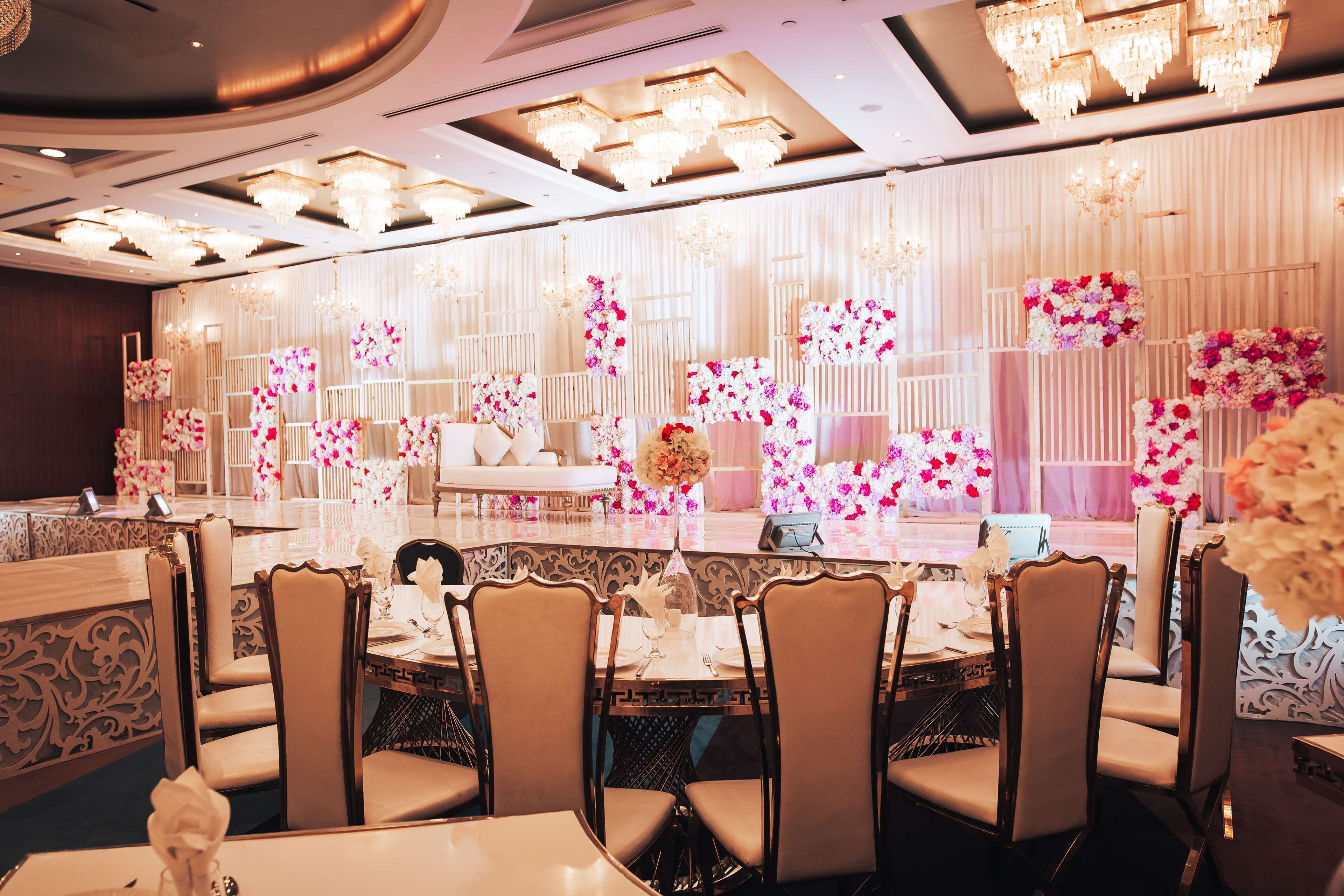 A formal dining area with chandeliers, white floral arrangements, and elegant table settings.