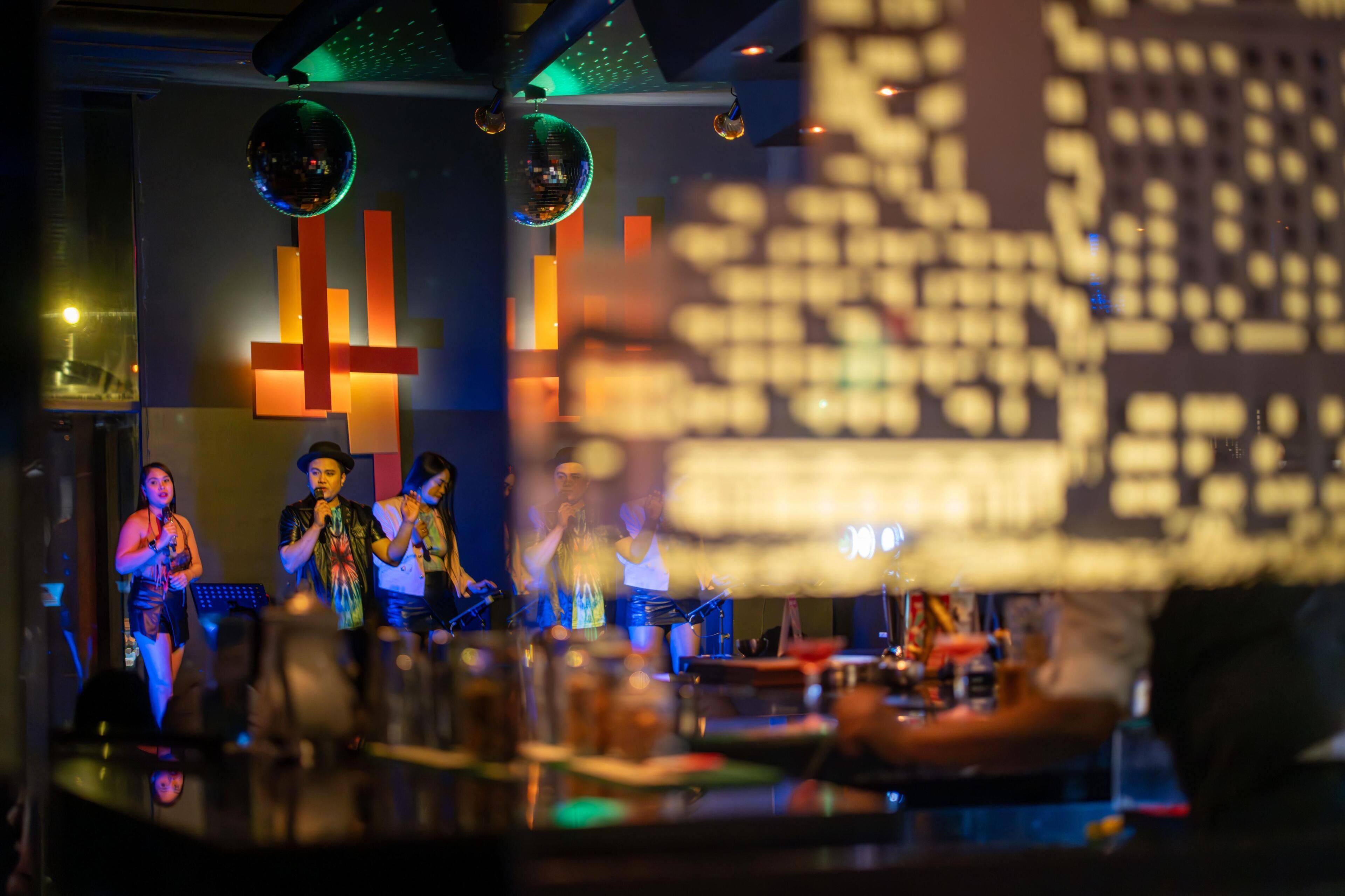 A bar with a stage, disco balls, and a large illuminated sign.