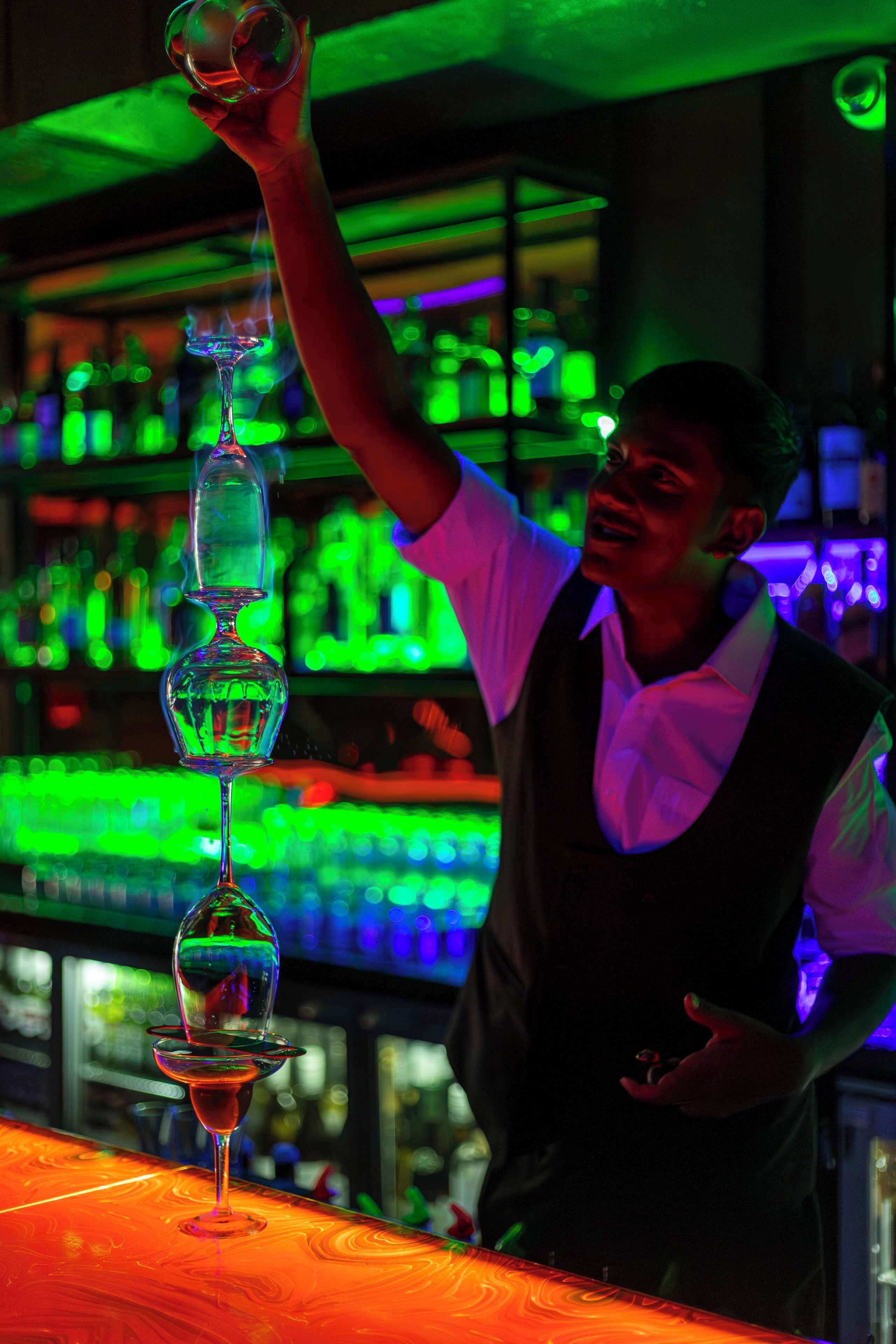 A bartender performing a trick with stacked wine glasses.