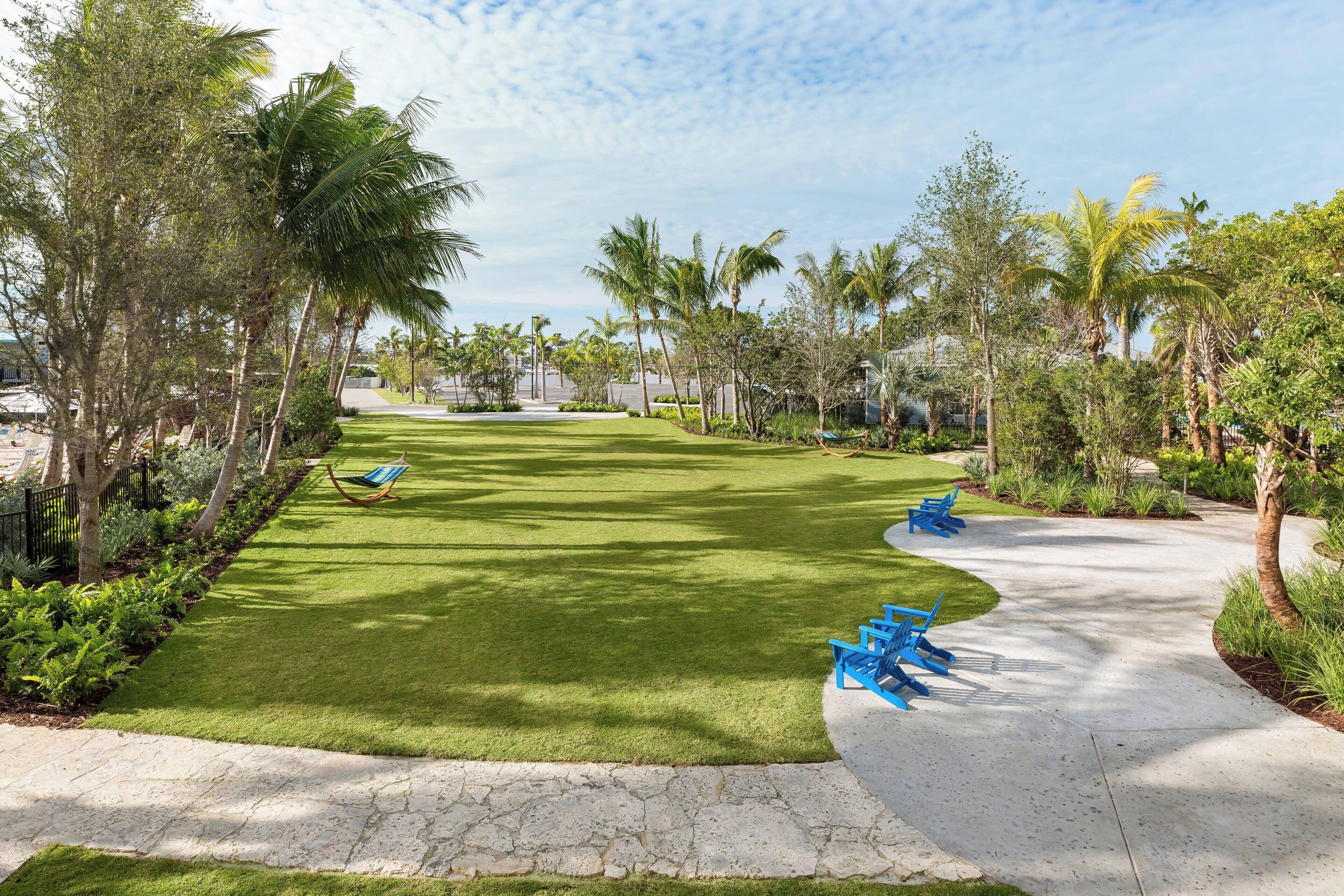 A well-maintained lawn with a curved pathway, surrounded by palm trees and greenery.