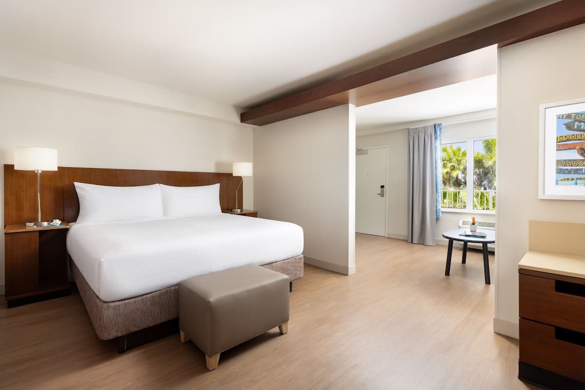 A hotel room with a large bed, a small table, and a desk.