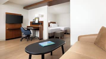 Una habitación de hotel con una cama, un escritorio, una silla, un televisor y un sofá.