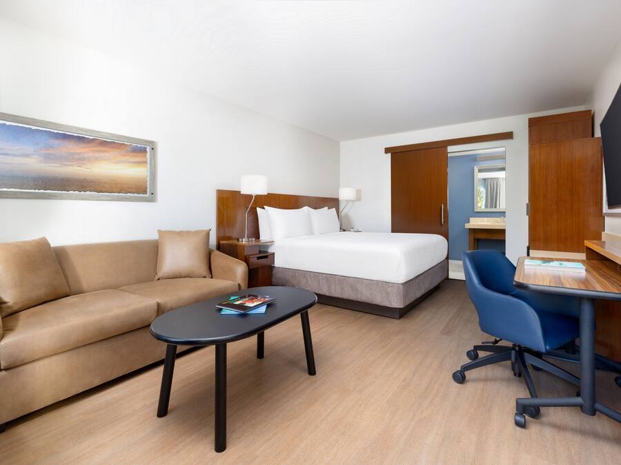 A hotel room with a bed, a sofa, a desk, and a TV.