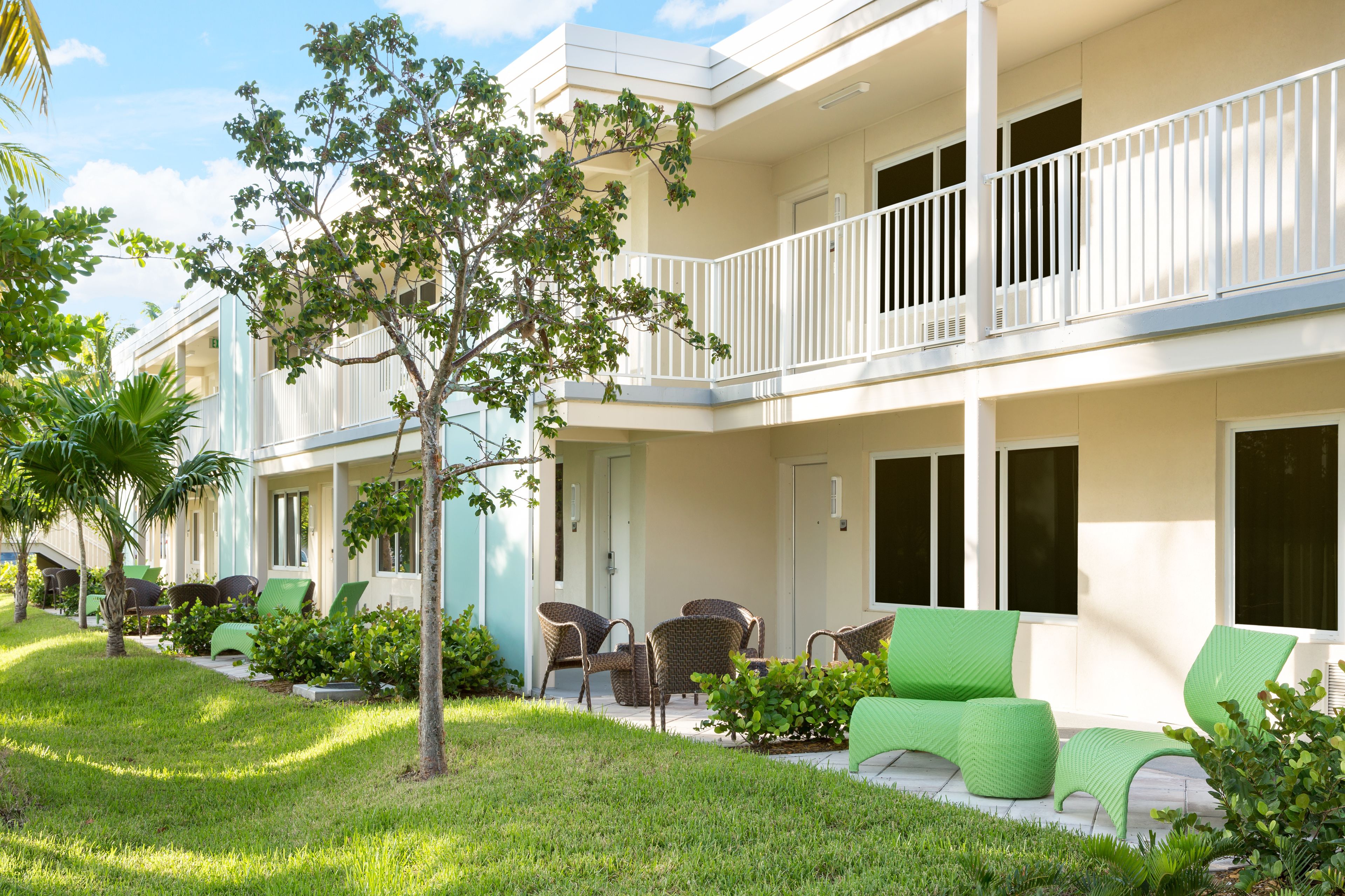 A hotel with a two-story structure, outdoor seating area with wicker furniture, and a well-maintained lawn.