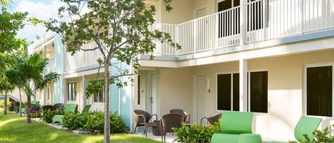 A hotel with a two-story structure, outdoor seating area with wicker furniture, and a well-maintained lawn.