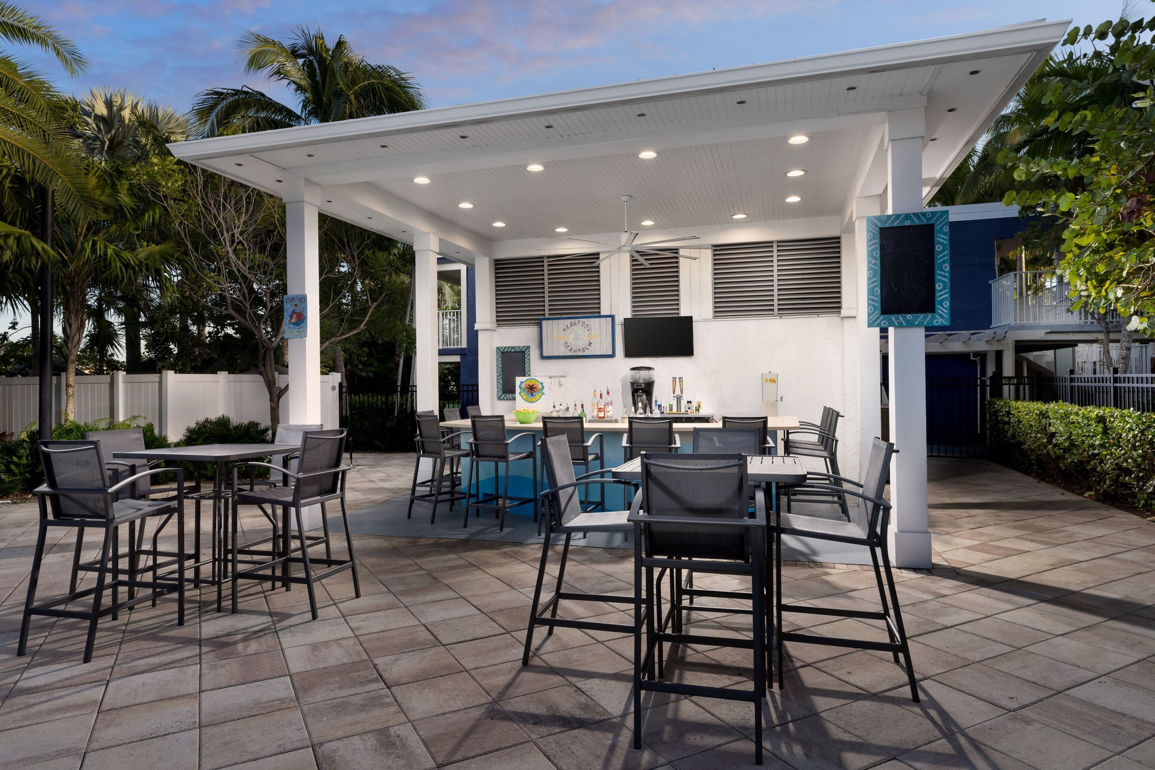 An outdoor patio area with tables and chairs, a bar, and a pool.