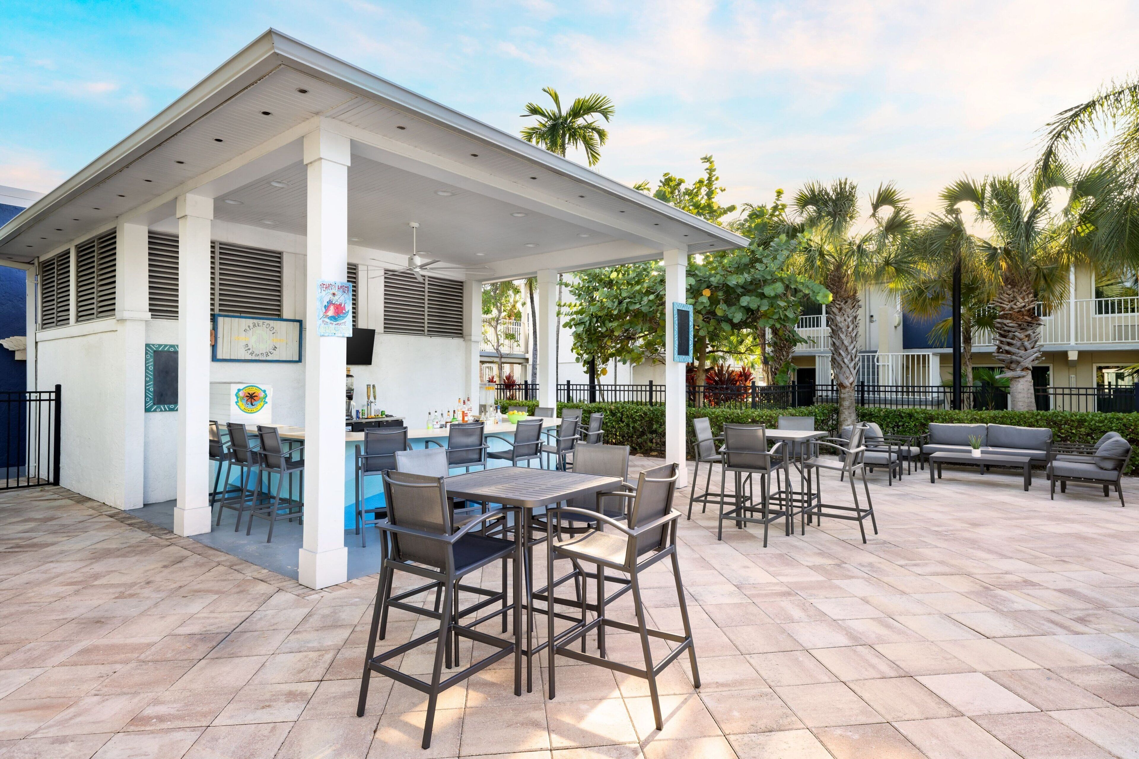 An outdoor patio with a covered seating area, bar, and poolside chairs.