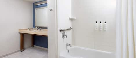 Un baño moderno con bañera, tocador con espejo y artículos de aseo en la pared.