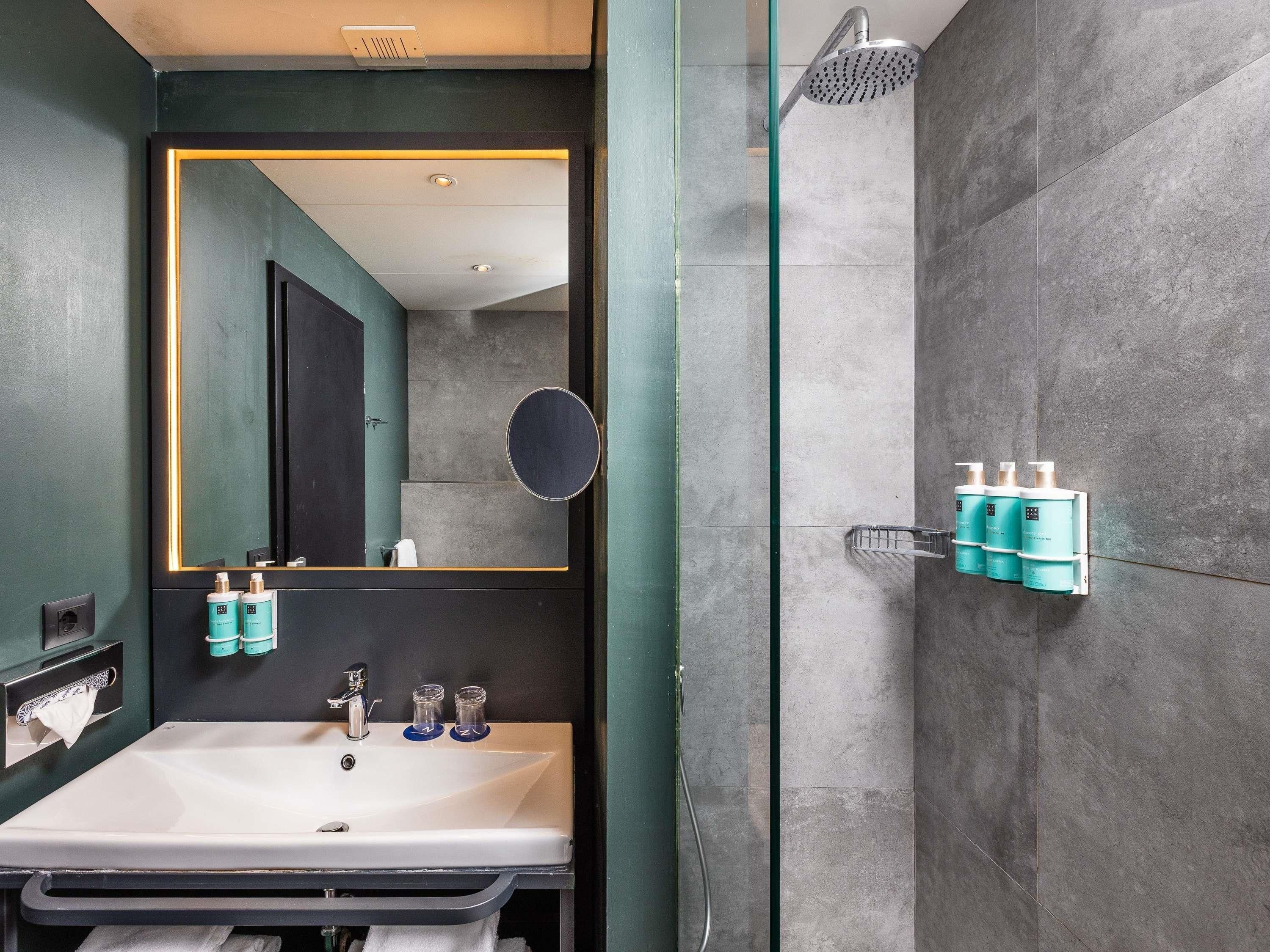 A modern bathroom with a large mirror, a sink, and a shower.