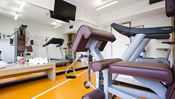 Una palestra con attrezzature per esercizi, una panca e un tapis roulant.