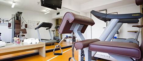 Un gimnasio con equipamiento de ejercicio, una banca y una cinta de correr.